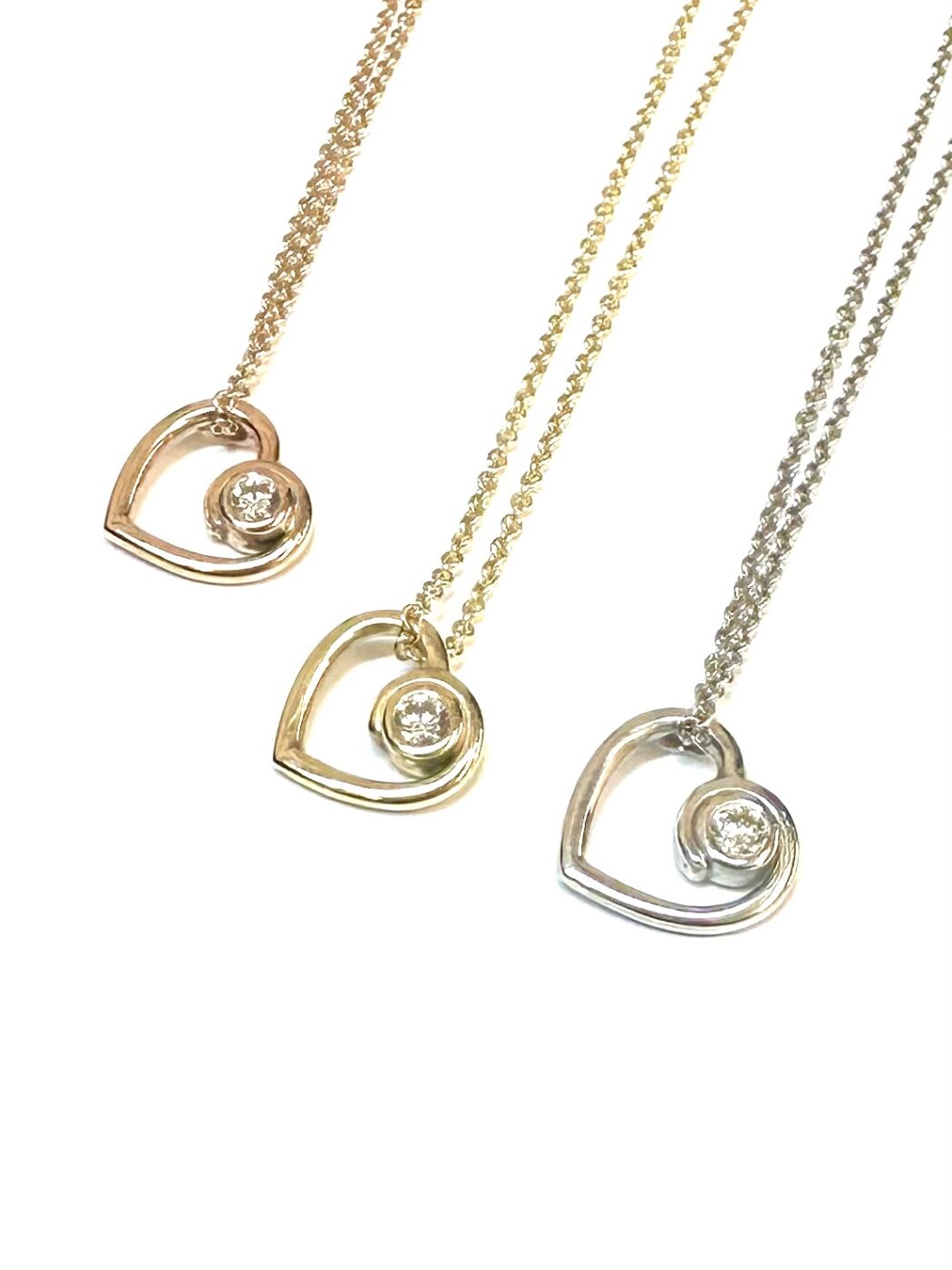 An open-heart diamond pendant, made in rose, yellow and white gold.